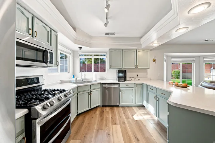Kitchen featuring wood-finish flooring, light-colored cabinetry, stainless steel appliances, white countertops, and recessed lighting