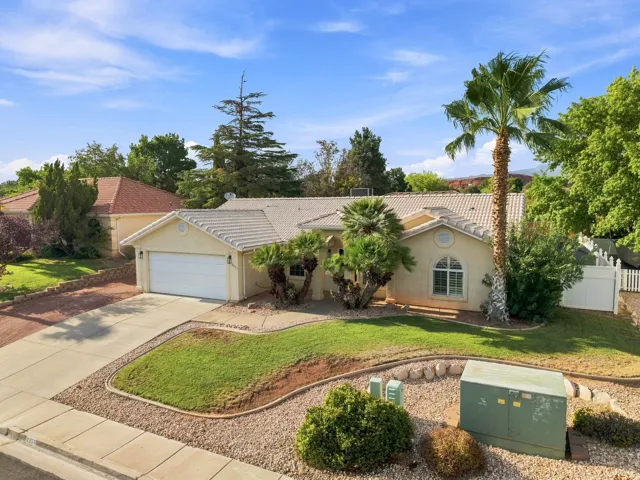 Single-story stucco exterior featuring a tile roof, an arched window, and an attached two-car garage