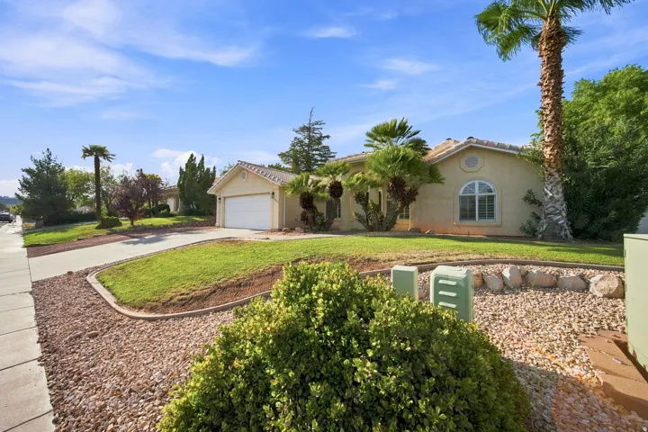 Stucco exterior with a tile roof, an arched window, an attached garage, and a concrete driveway