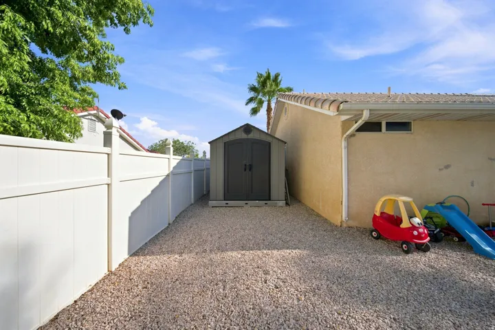 Gravel ground cover, vinyl fencing, storage shed, stucco exterior, and tile roofing
