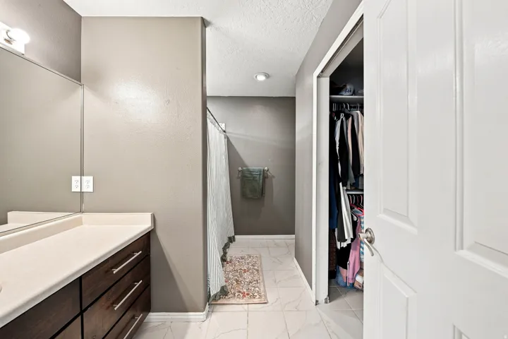 Vanity with wood-finish cabinetry, light-colored countertop, and integrated mirror