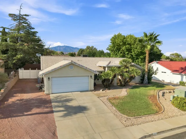 Single-story residence featuring an attached two-car garage, concrete driveway, and a white picket fence