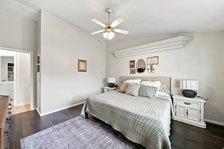 Vaulted ceiling with a ceiling fan, dark wood-finish flooring, and white baseboards