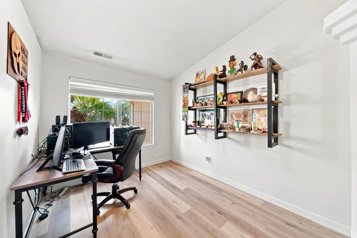 Recessed window with exterior foliage, wood-finish flooring, white walls, and built-in shelving