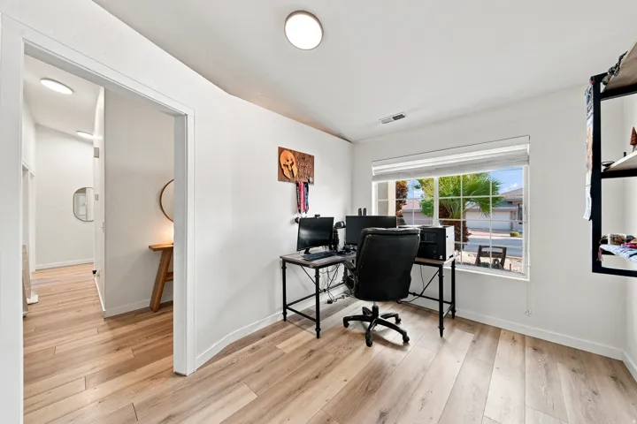 Wood-finish flooring throughout, bright white walls, recessed ceiling lighting, and a window with blinds