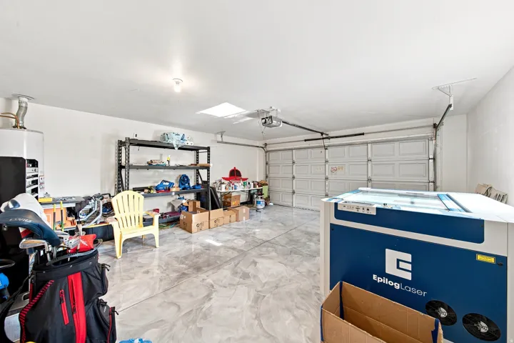 Two-car garage with a sectional overhead door, a skylight, and a concrete floor