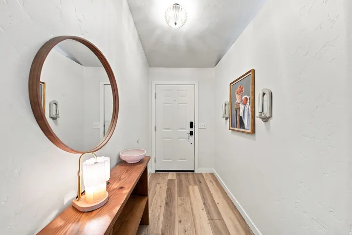 Entryway featuring wood-finish flooring, a white paneled door, and textured wall finishes