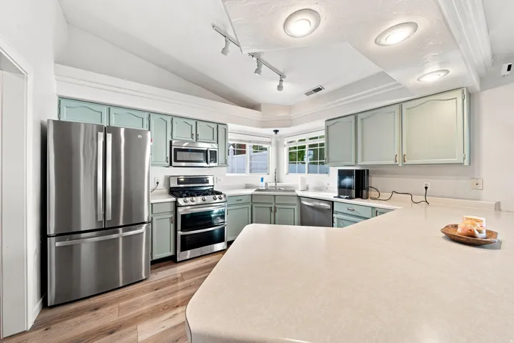 Kitchen featuring wood-finish flooring, stainless steel appliances, recessed lighting, light-toned countertops, and accent cabinetry