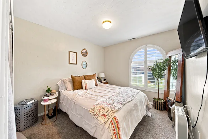 Arched window with plantation shutters, ceiling-mounted light fixture, and textured walls