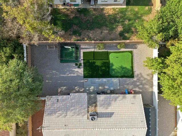 Expansive backyard featuring a putting green, artificial turf, and gravel landscaping