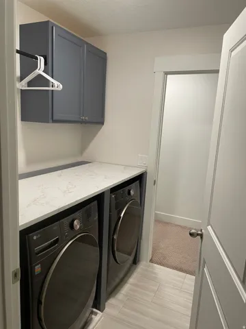Laundry area featuring gray cabinetry, a white countertop, and light-toned tile flooring