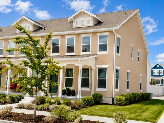Stucco exterior with white trim, multiple windows, and dormer details