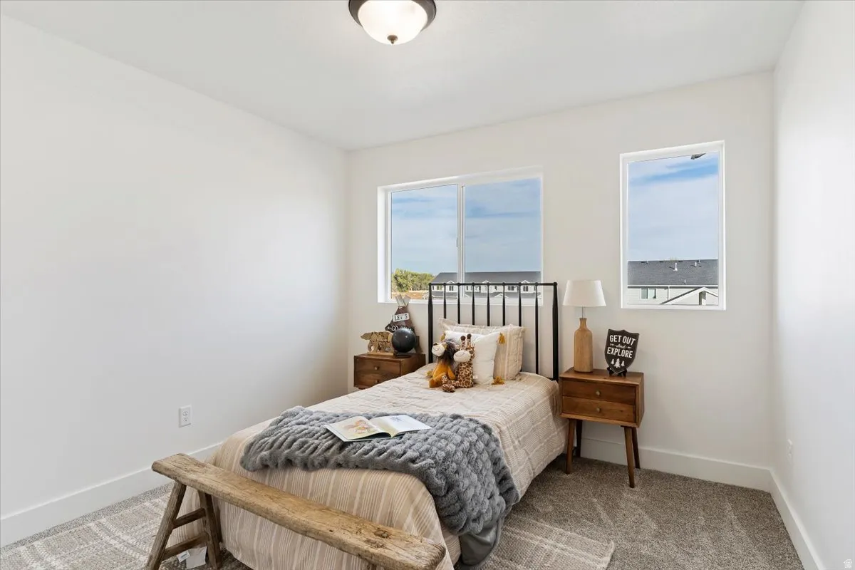 White painted walls, two windows, carpet flooring, base molding, and a flush mount ceiling light fixture