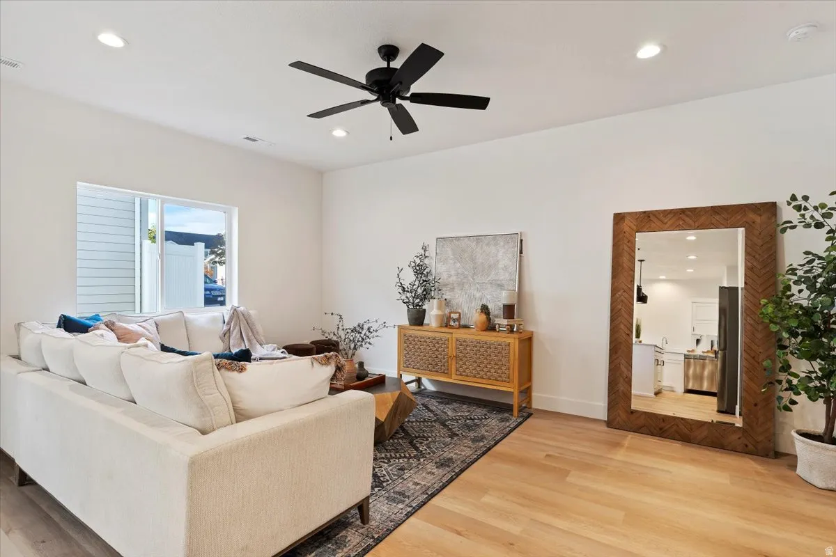 Recessed lighting, light wood-finish flooring, a black ceiling fan, and a wood-frame mirror