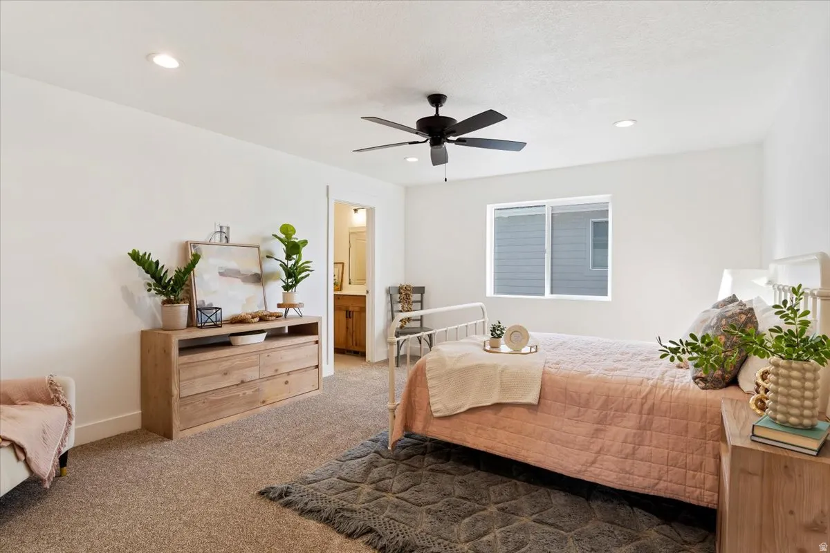 Recessed lighting, ceiling fan, window with exterior siding visible, and a doorway leading to a room with a wood-finish vanity