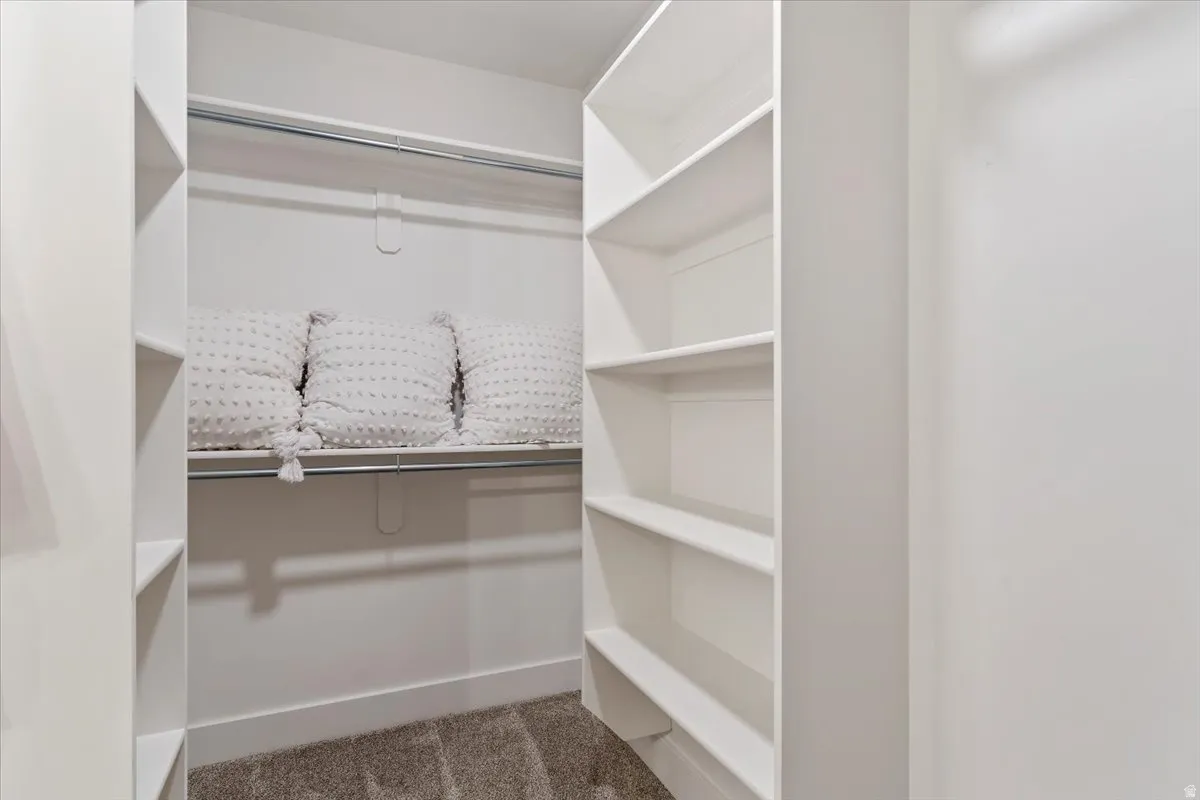 Spacious walk-in closet featuring built-in shelving throughout, a sturdy rod system for hanging storage, and neutral finishes with soft lighting for optimal visibility and organization