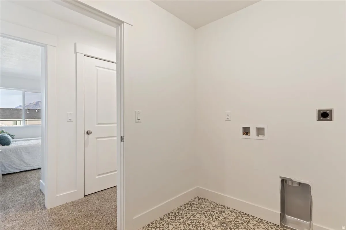 Dedicated utility area featuring patterned floor tile and appliance hookups