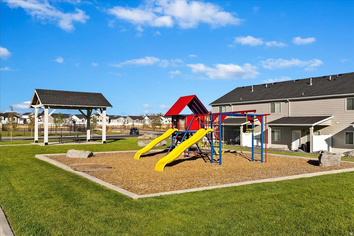 Open green space featuring a playground with slides and climbing structures, along with a covered picnic area