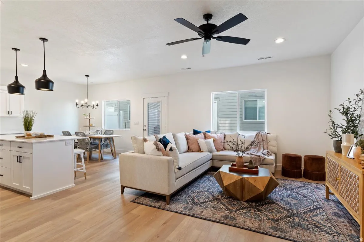 Open-concept living area with light wood-finish flooring, recessed lighting, and a contemporary ceiling fan