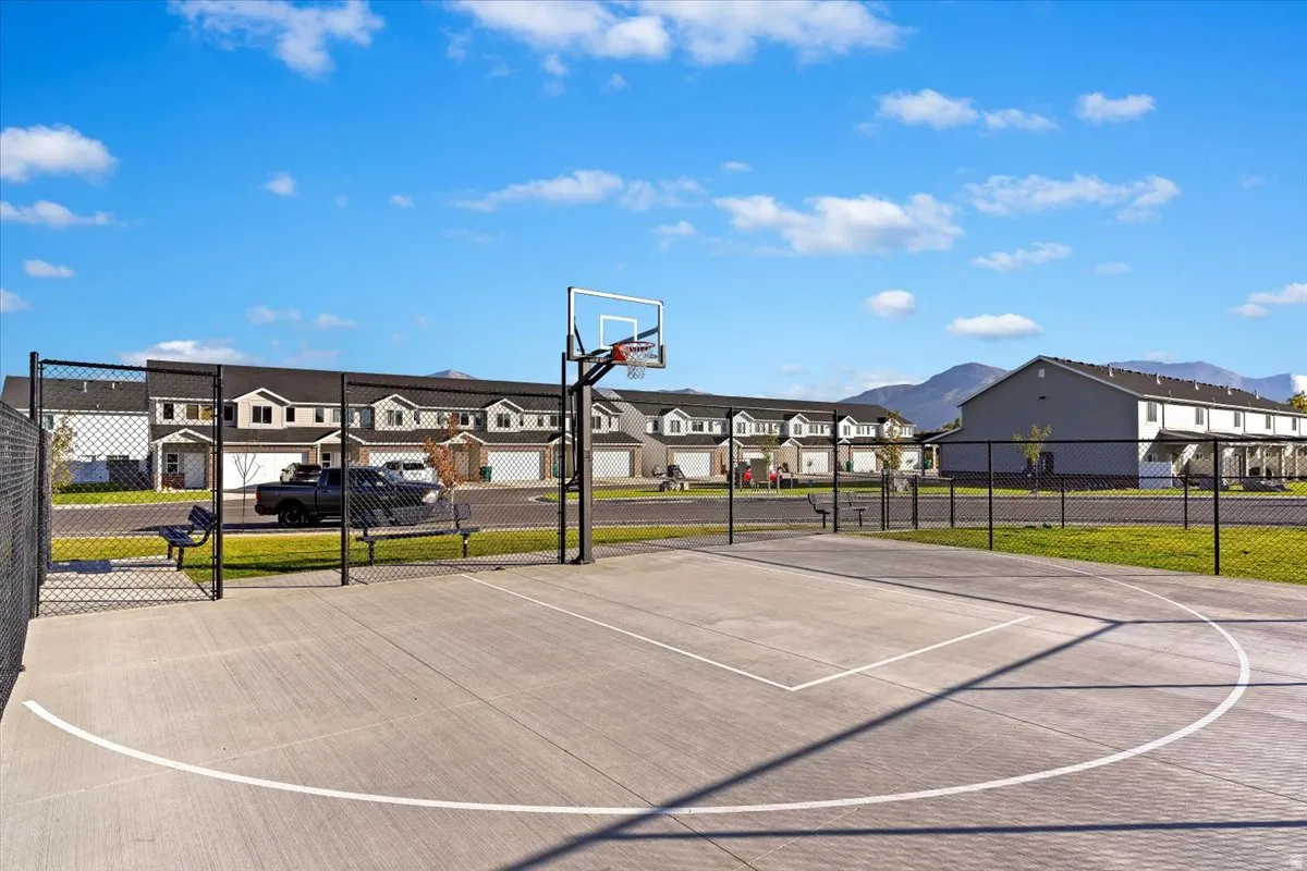 Concrete basketball court with chain-link fencing, mounted backboard, and court lines