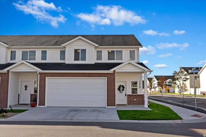 Brick and siding exterior with a dark roof, attached garage, covered entryway, and concrete driveway