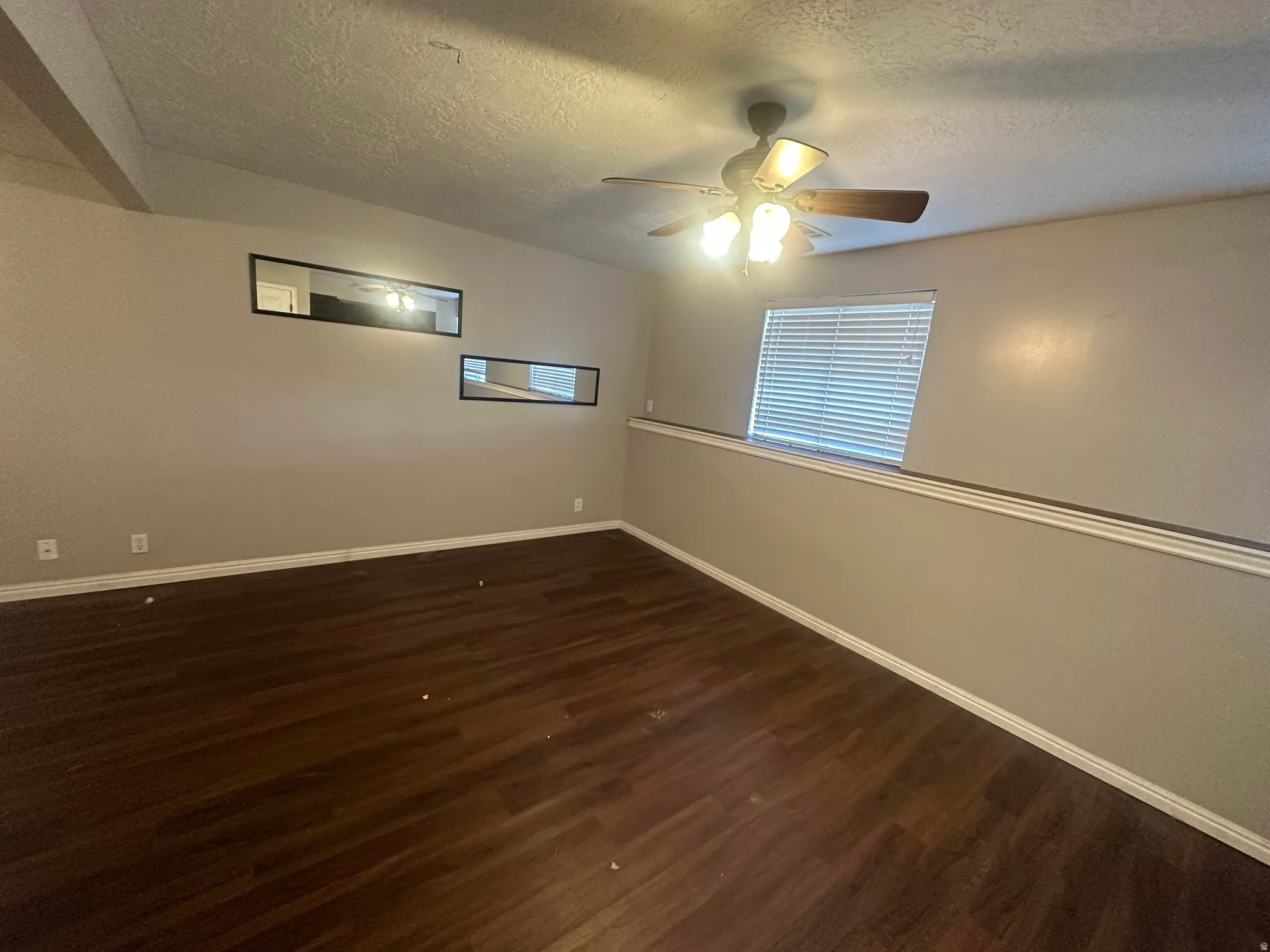 Wood-finish flooring, ceiling fan with integrated lighting, window with blinds, and neutral wall tones