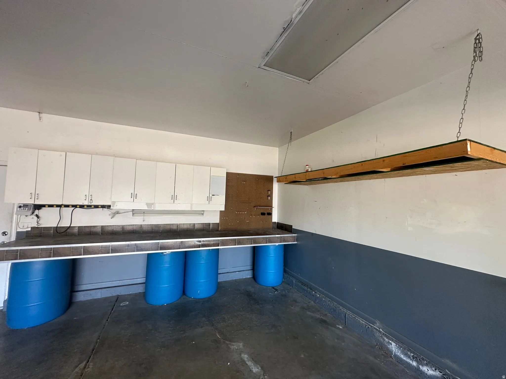 Built-in cabinetry, overhead shelving, work surface, and ceiling-mounted fluorescent lighting