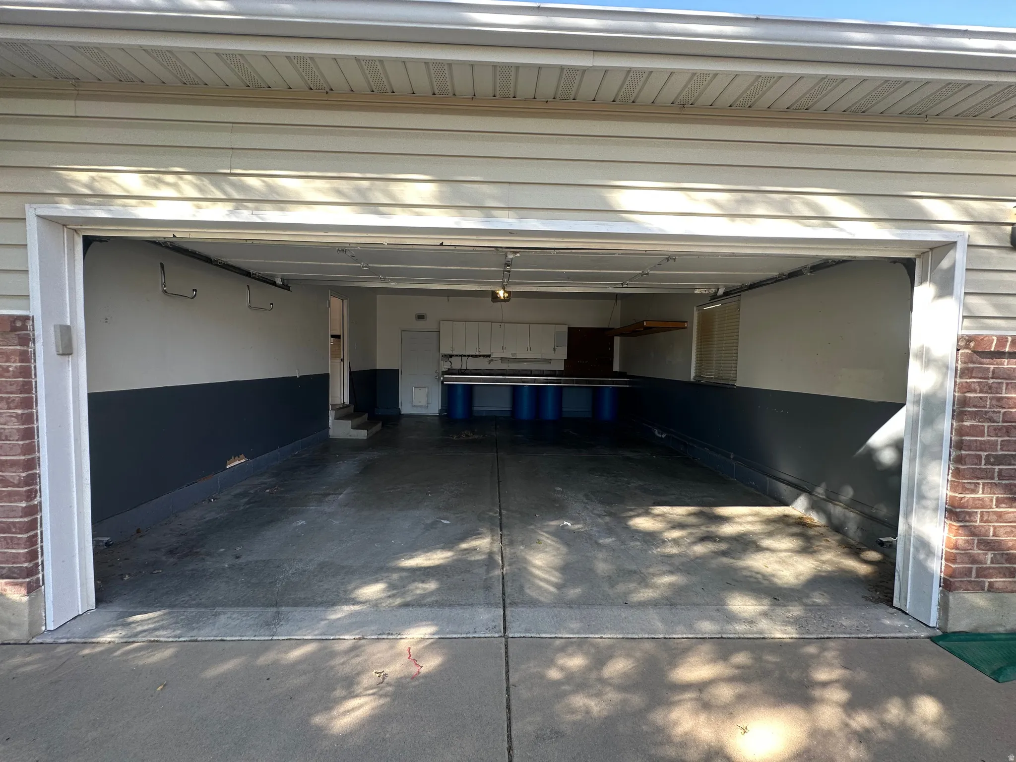 Two-car garage with concrete flooring, built-in shelving, and exterior brick siding accents