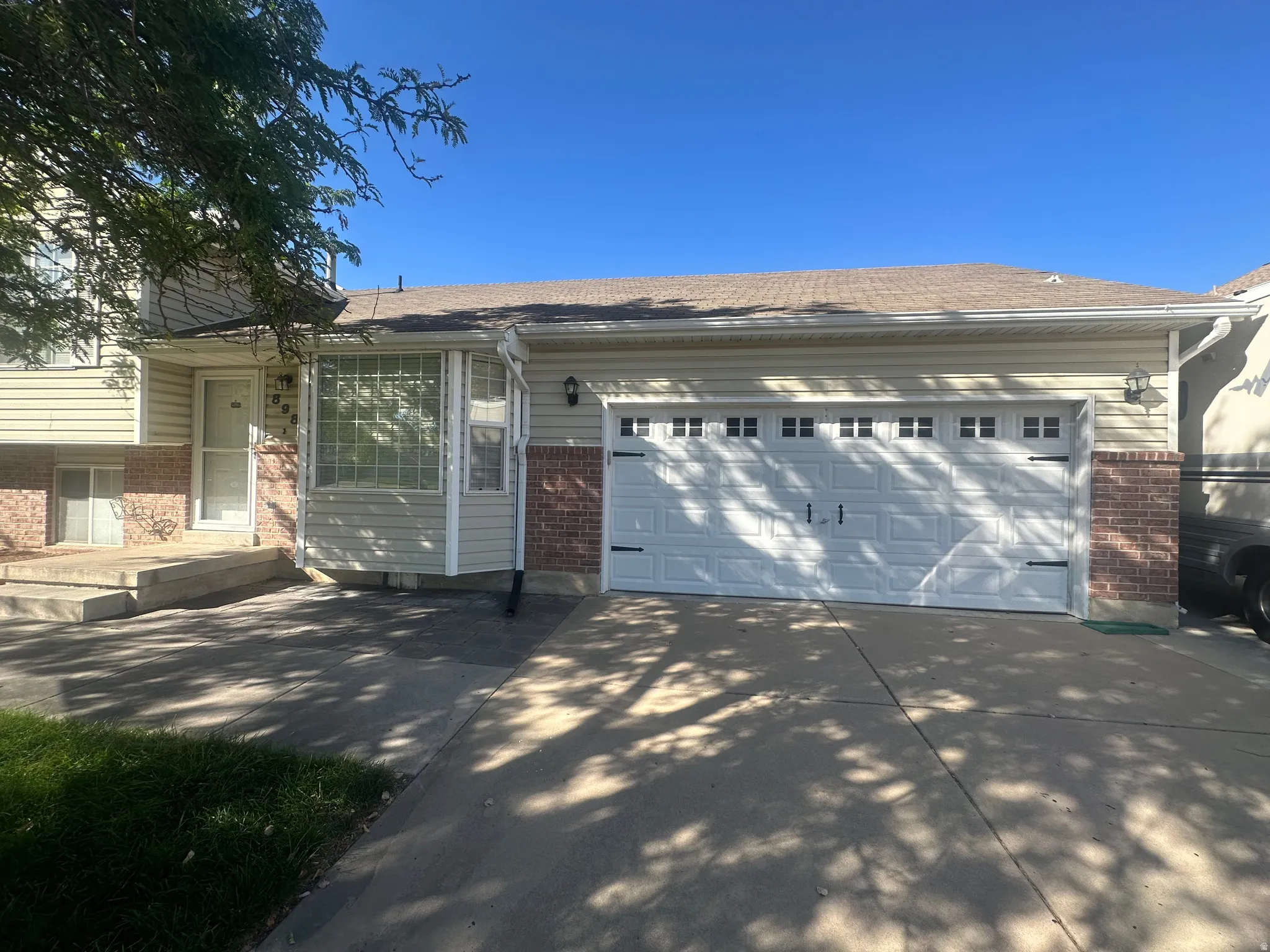 Two-car garage with paneling and decorative hardware, brick accents, and a front entry with a storm door