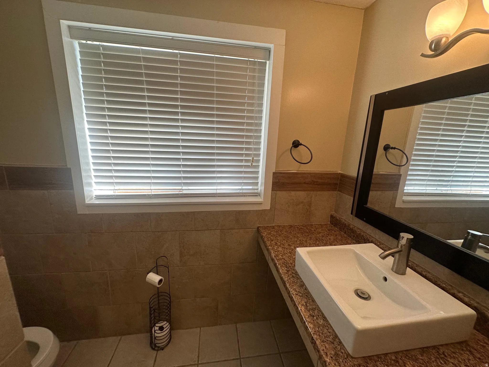 Rectangular vessel sink with a single-handle faucet, granite-finish countertop, and tiled wainscoting