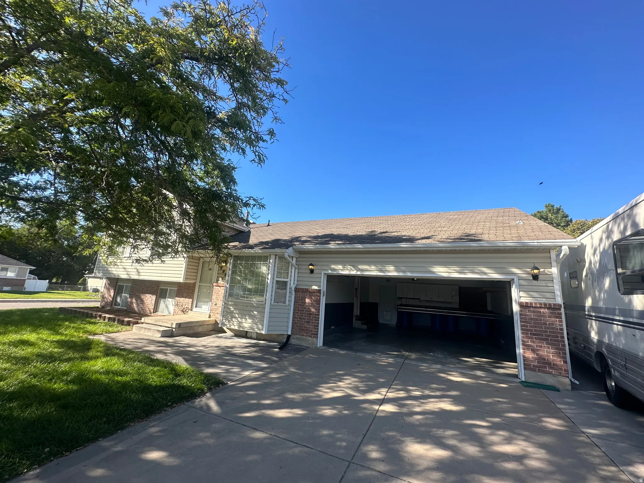 Spacious driveway with concrete surface and attached two-car garage featuring open bay doors