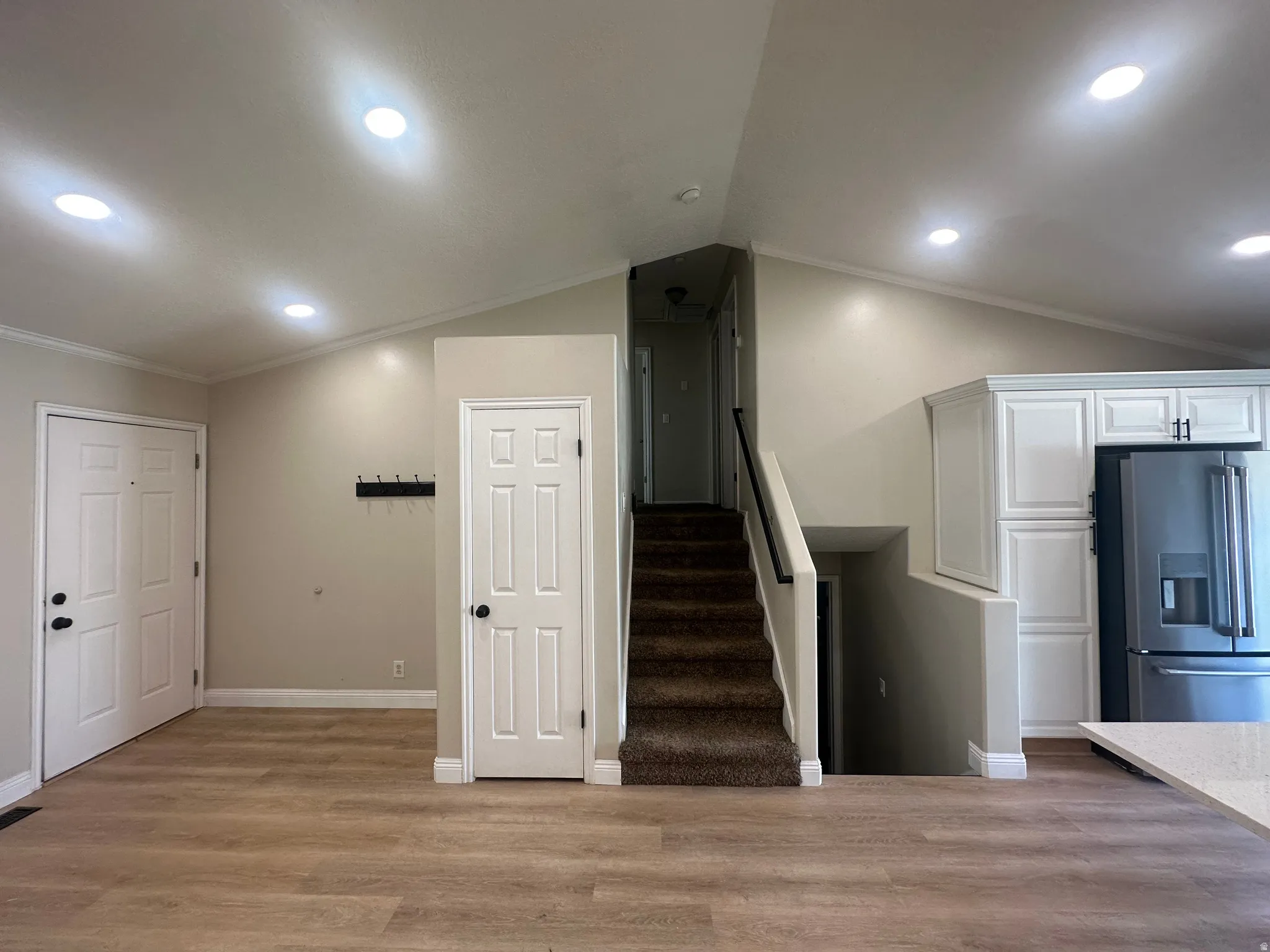 Open floor plan featuring wood-finish flooring throughout, recessed lighting, and a central staircase with dark treads and metal railings