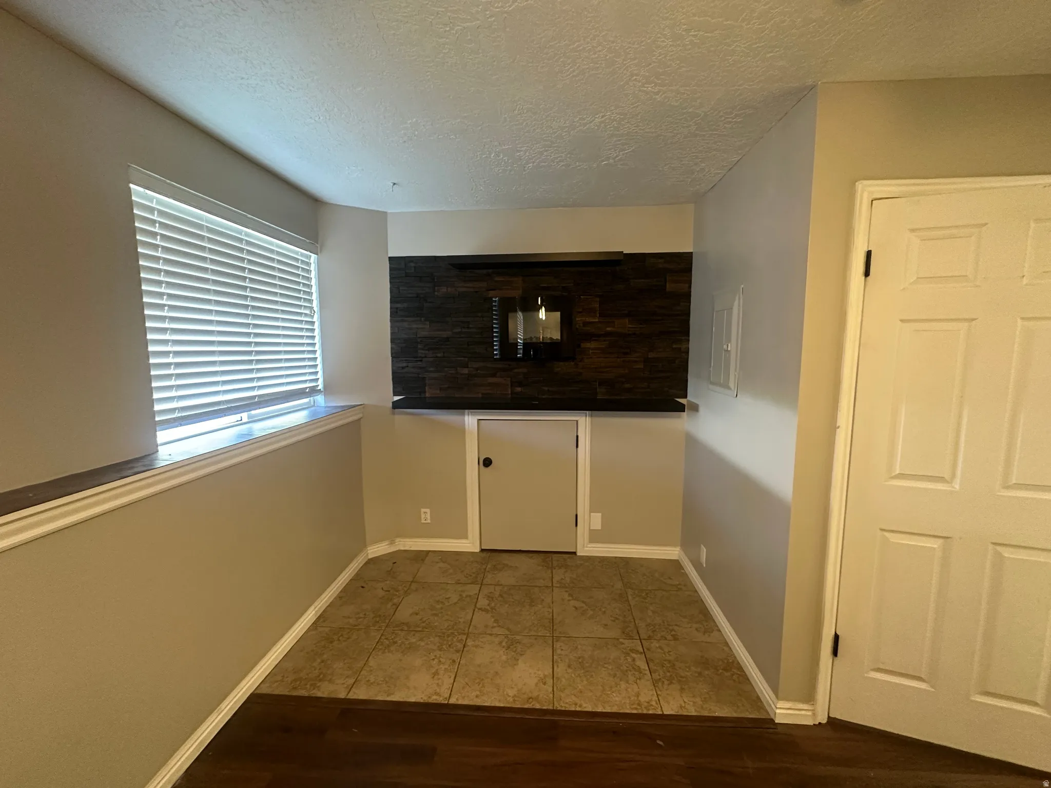 Built-in bar with stone-look accent wall, integrated lighting, and a dark countertop