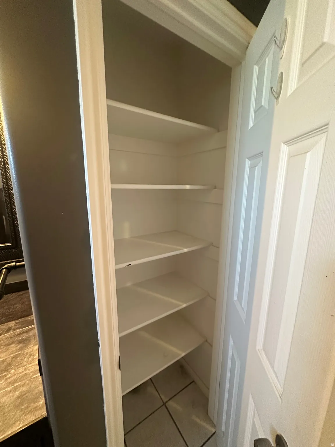 Built-in shelving with multiple storage levels, tiled flooring, and a paneled door