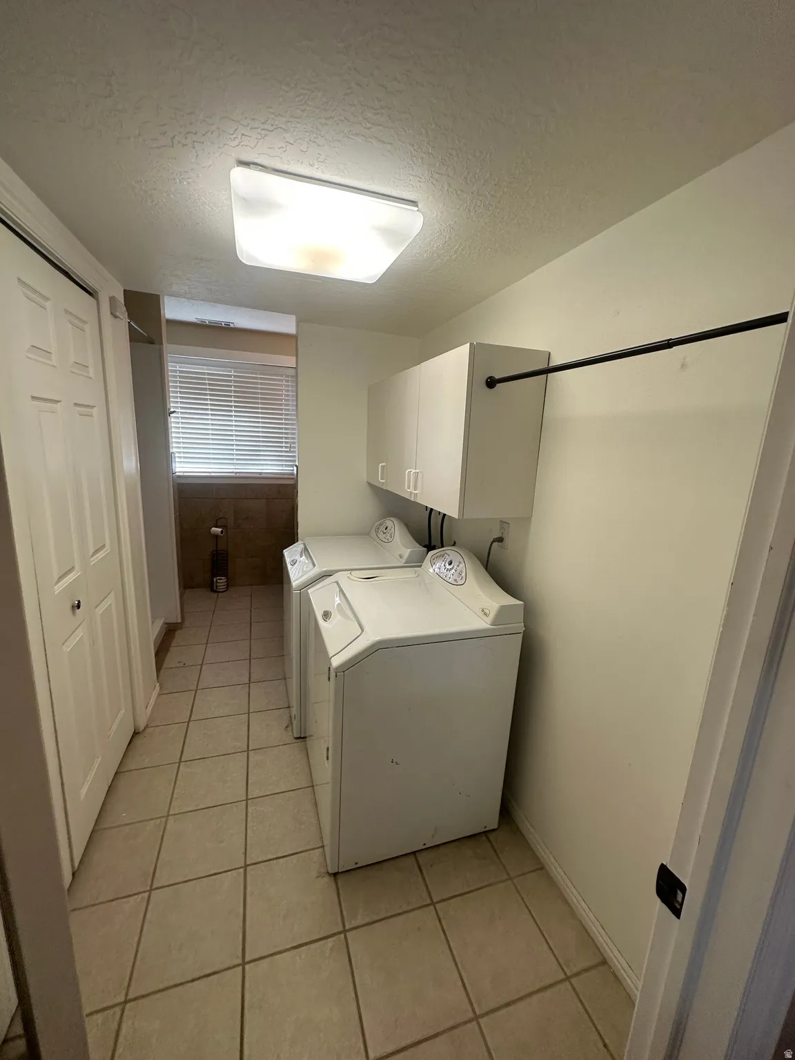 Ceramic tile flooring, built-in upper cabinetry, and a clothing rod