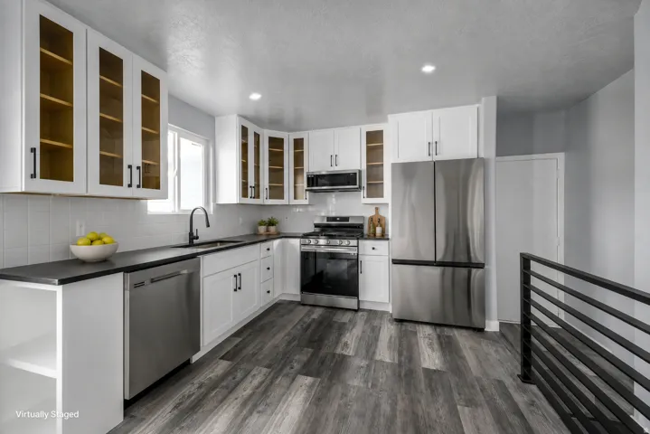 Kitchen featuring white cabinetry, dark countertops, a stainless steel appliance suite, and wood-finish flooring