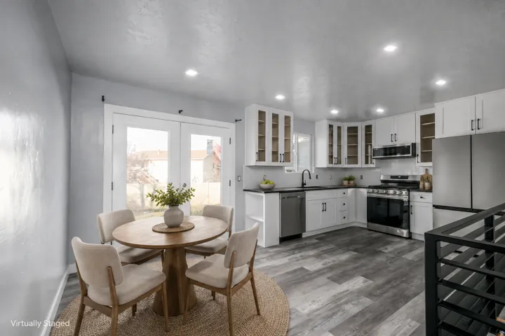White cabinetry with dark hardware, stainless steel appliances, wood-finish flooring, recessed lighting, and a subway tile backsplash