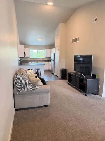 Vaulted ceilings defining a spacious living area with wall-to-wall carpeting