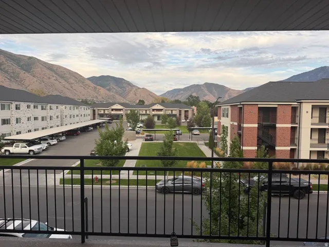 Mountain scenery, community green space, covered parking structures, black metal balcony railing, brick building facade