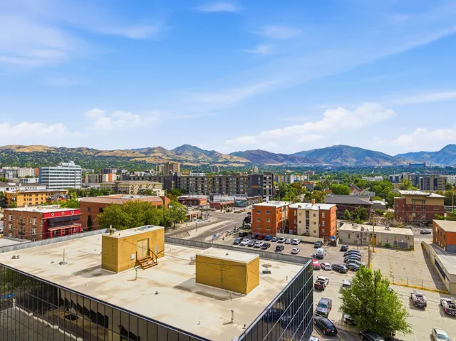 Cityscape with varied building architecture and distant mountain ranges under a clear sky