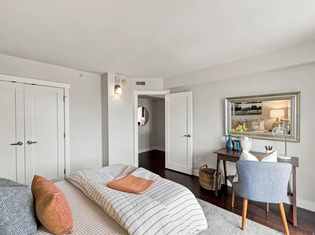 Dark wood-finish flooring, white paneled doors, and wall-mounted sconce