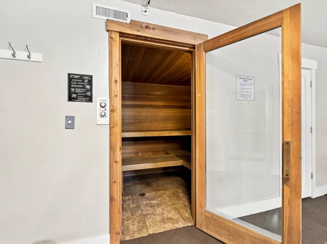 Cedar-paneled sauna featuring built-in wooden benches and tiled flooring