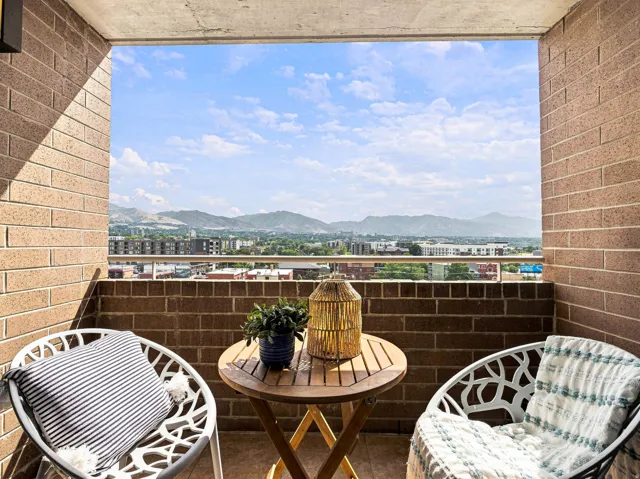 Brick-walled balcony featuring a concrete ceiling, metal railing, and expansive mountain scenery