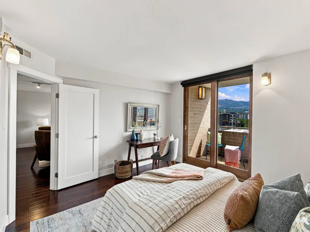Hardwood flooring, white interior doors, sliding glass balcony door, brick balcony wall, and wall-mounted light fixtures