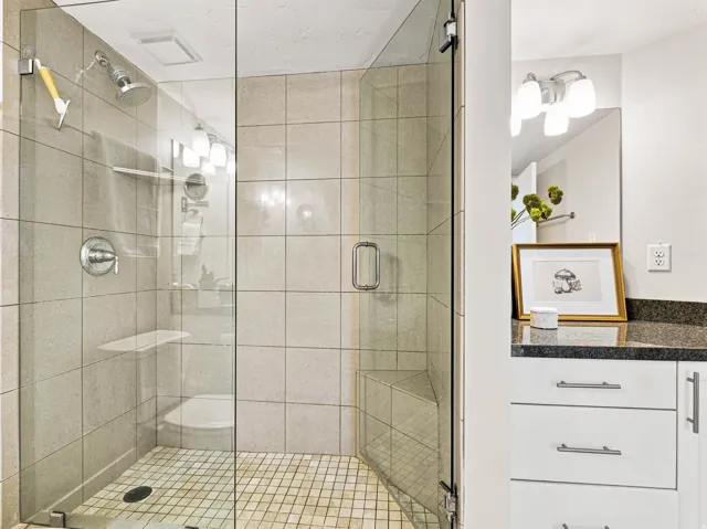 Glass-enclosed shower with a built-in bench, tiled walls, and a tiled shower floor