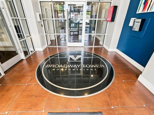 Grand foyer showcasing polished wood-finish flooring with inlaid circular medallion detail, dual glass and white-frame French doors with sidelights, white coffered ceiling, and access to multiple rooms
