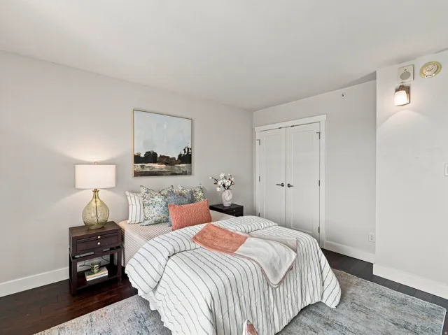 Dark wood-finish flooring, white walls, and built-in closet with white doors