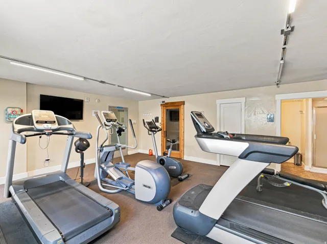 Dedicated fitness space featuring neutral wall tones, track lighting, and carpeted flooring