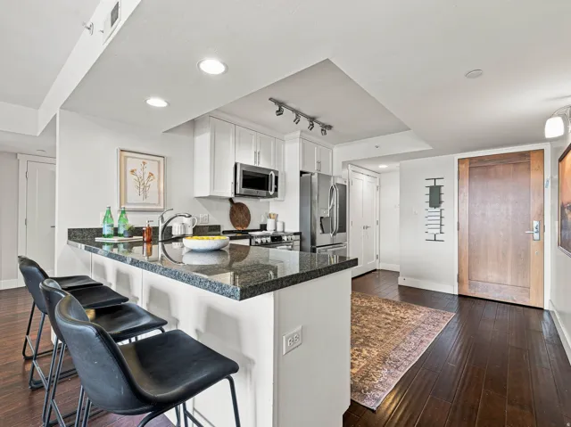 Kitchen with granite countertops, white cabinetry, stainless steel appliances, and a breakfast bar