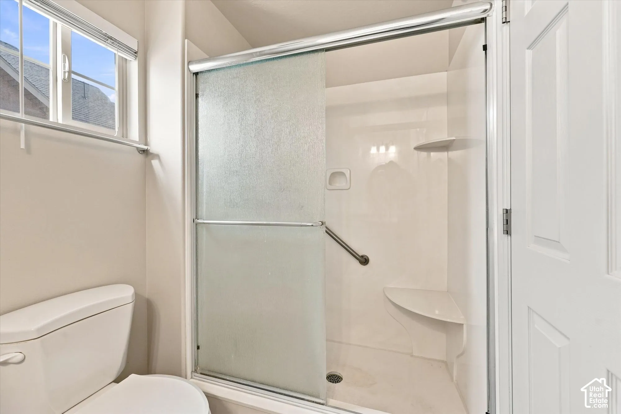 Shower enclosure with frosted glass panels, built-in seating, and a grab bar